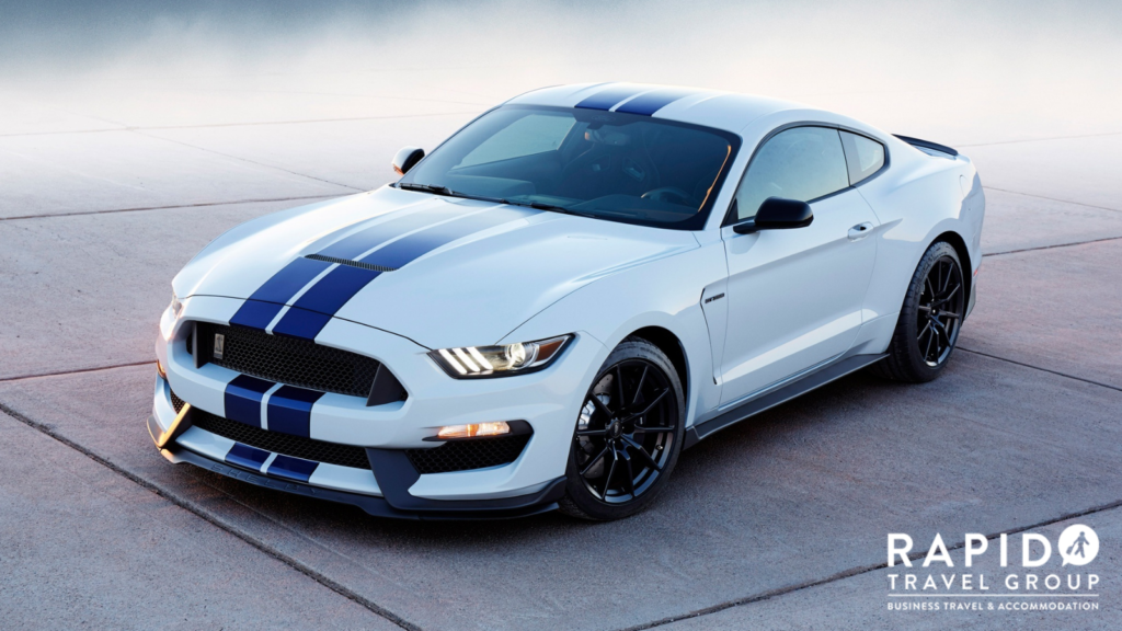 A Ford Mustang Shelby in white with two thick blue stripes going across the top of the car.. The Rapid logo is in the bottom right corner.